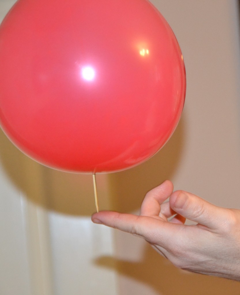 A wooden spike pierced a balloon as a scientific demonstration.
