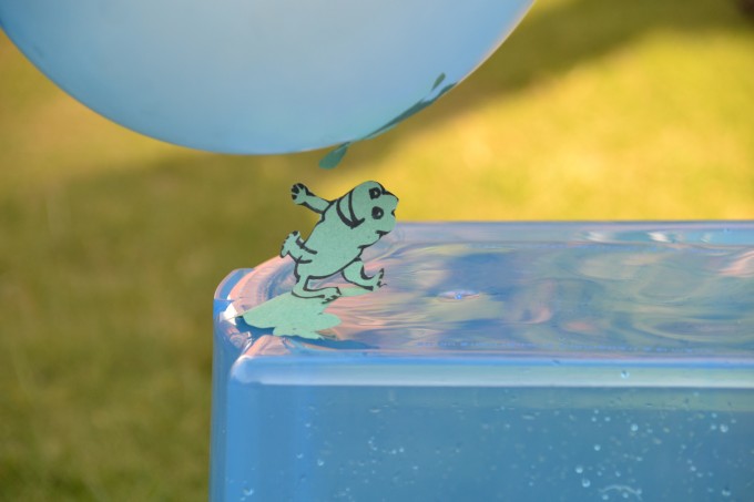 A tissue paper frog shape jumping up to a blue balloon that has been charged with static electricity
