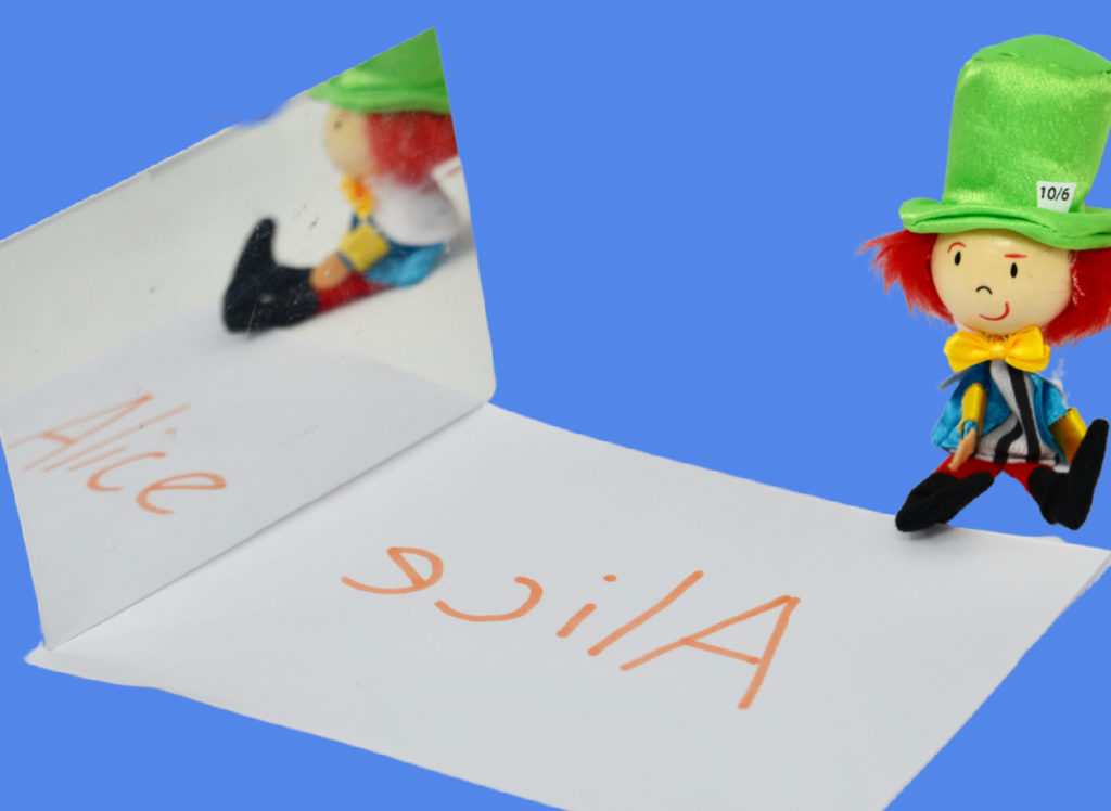 Image of a mad hatter toy, paper with Alice written on it and a mirror