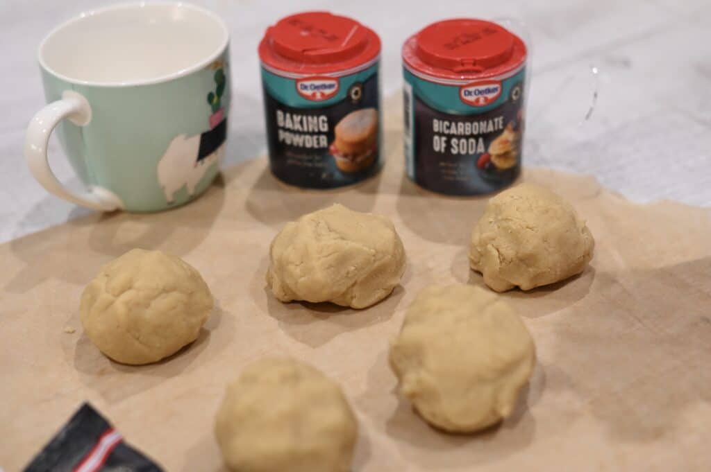 five balls of cookie dough, baking powder and bicarbonate of soda for a baking science experiment